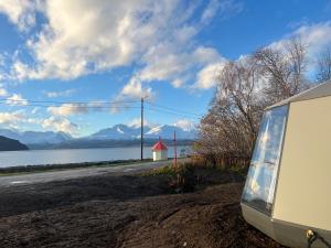 a van parked on the side of a road next to a lake at Northern Lights AuroraHut Lyngenfjord, by Alpan Apartments in Olderdalen