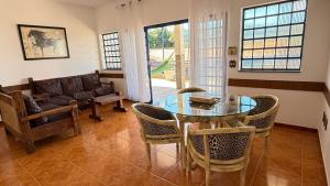 a living room with a glass table and chairs at Nova Aliança Suítes por Temporada em Amparo NÃO SOMOS POUSADA in Amparo