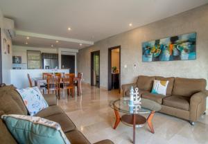 a living room with couches and a table and a kitchen at A10- Roble Sabana 201 in Playa Conchal +33 photos