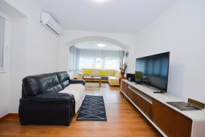 a living room with a couch and a television at Casa do Cantinho do Muro in São Vicente
