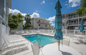 una piscina con sillas y sombrilla en un complejo turístico en Gulf Sands – 3BR Steps to Pool & Private Beach, en Punta Gorda Beach