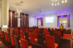 a conference room with red chairs and a screen at Golden Bay Beach Hotel in Larnaca