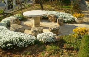 a stone bench in a garden with white flowers at Cozy Apartment In Omis With House Sea View in Tice