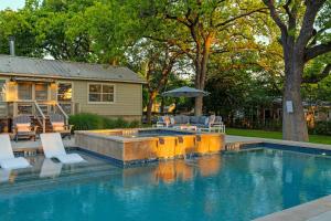 een zwembad met stoelen en een parasol naast een huis bij Luxury Family Stay with Heated Pool Spa Fire Pit Games in Fredericksburg