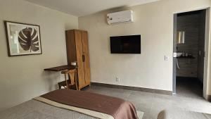 Un dormitorio con una cama y un televisor en la pared. en Florestina Búzios, en Búzios