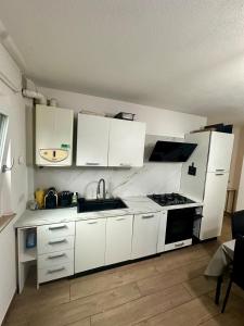 a kitchen with white cabinets and a sink and a stove at Lake Apartment Gold, Lago di Caldonazzo in Tenna  +18 photos