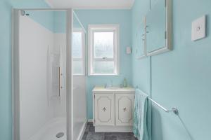 een blauwe badkamer met een wastafel en een douche bij Boxed Bliss on Fox in Hamilton