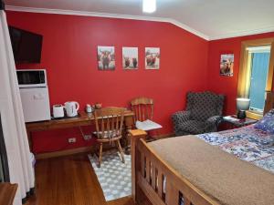 a bedroom with a red wall with a bed and a desk at The Highlander in Flowerdale