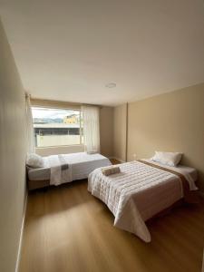 twee bedden in een kamer met een groot raam bij Casa Terminal Terrestre in Loja