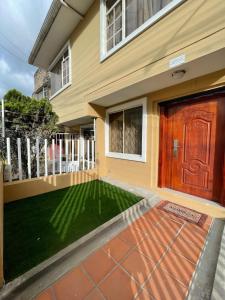 een huis met een groen gazon voor een deur bij Casa Terminal Terrestre in Loja