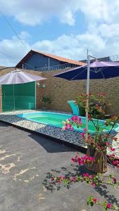 ein Pool mit Sonnenschirm und ein paar Blumen in der Unterkunft Castanhal na Cop30 in Castanhal + 9 Fotos
