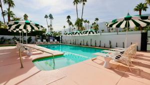 uma piscina com espreguiçadeiras e guarda-sóis em The Marley by AvantStay Mid-Century Modern Retreat with Pool & Mountain Views em Palm Springs