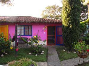 Melao Hostel Campestre y Vivero في بالميرا: منزل وردي اللون مع باب ملون في الفناء