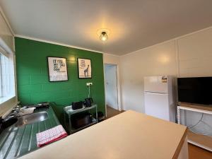 a kitchen with a sink and a green wall at Peppertree Lodge in Paihia