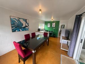 a dining room with a table and red chairs at Peppertree Lodge in Paihia