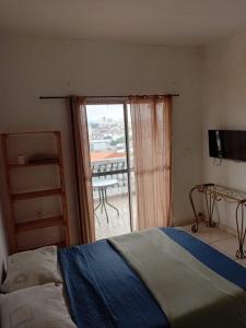 a bedroom with a bed and a window with a balcony at Kit com varanda in Sao Paulo