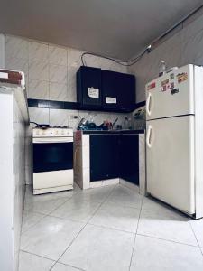 a small kitchen with white appliances and blue cabinets at Habitacion privada cerca al hospital de Neiva con Aire Acondicionado y baño Privado in Neiva