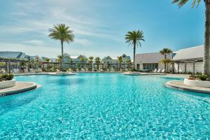a large swimming pool with palm trees and buildings at Sea Haven At Prominence in Watersound Beach