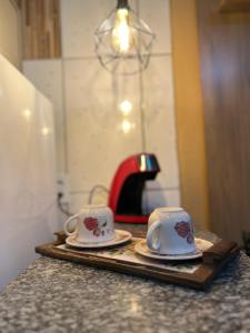 two cups and saucers on a tray on a counter at Studio prático e bem localizado em Cuiabá in Cuiabá +10 photos