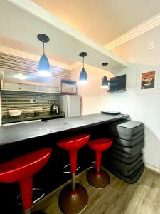 Una cocina con dos taburetes rojos y un mostrador. en Sky pool São Vicente, en São Vicente