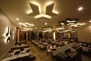 a restaurant with tables and chairs and a large chandelier at Hotel Arizona Inn in Anand