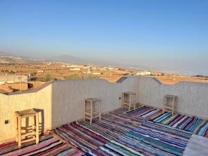 a room with a rug on a wall with stools at Dar lkbira Azazoul in Taghazout +10 photos