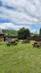 a group of picnic tables in a grass field at Pentwyn avenue apartment in Mountain Ash