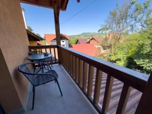 a balcony with a table and chair and a view at Pensiunea NikoBella Panzió in Sovata