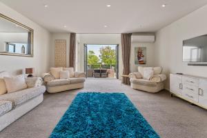 a living room with two couches and a blue rug at Stay Central Taupo in Taupo