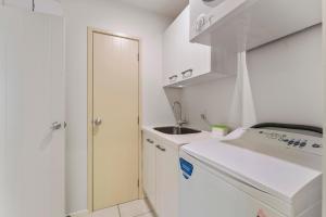 a small white kitchen with a sink and a washing machine at Stay Central Taupo in Taupo +24 photos