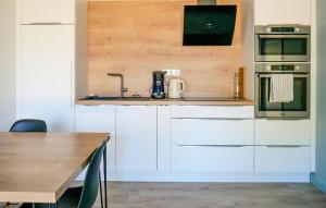 Una cocina con gabinetes blancos y una mesa de madera. en 2 Bedroom Gorgeous Home In Allan, en Allan