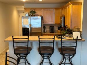Una cocina con una barra con tres taburetes y un refrigerador. en Lake Front and Calm Waters at Miramar 3BR 2BA, en Camdenton