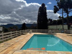 una piscina con una valla y montañas en el fondo en Casa em Campos do Jordao com Vista da Pedra do Bau, en Santa Clara