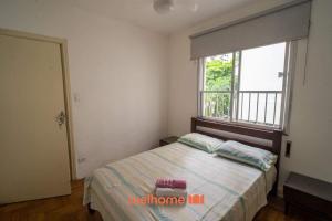 ein Schlafzimmer mit einem Bett und einem großen Fenster in der Unterkunft Apartamento no Guaruja 50m da Praia das Pitangueiras in Guarujá