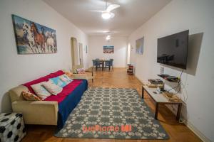 ein Wohnzimmer mit einem roten Sofa und einem Tisch in der Unterkunft Apartamento no Guaruja 50m da Praia das Pitangueiras in Guarujá