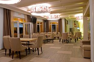 a dining room with tables and chairs and chandeliers at Marseille Resort in Zatoka