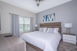 a white bedroom with a large bed and a window at 4809AM TOWNHOUSE 4 BEDROOMS & 3 BATHROOMS + POOL in Kissimmee +18 photos