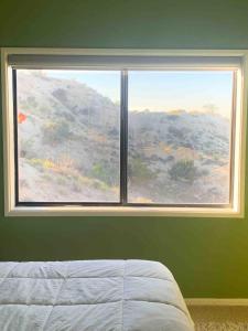 a bedroom with a large window with a mountain view at Mountainside Retreat in Yucca Valley