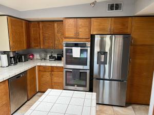 a kitchen with a stainless steel refrigerator and wooden cabinets at Mountainside Retreat in Yucca Valley +55 photos