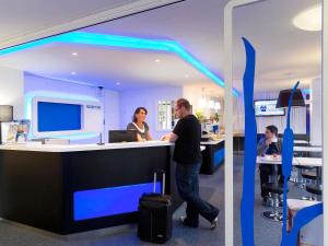 a man and a woman standing at a counter at ibis budget Albertville in Gilly-sur-Isère