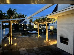 a deck with trees and lights in front of a house at by the water in Friesland NI in Stavoren