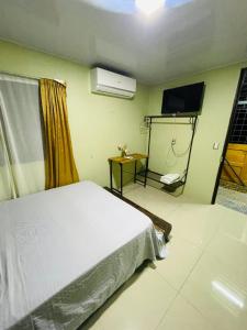 a bedroom with a bed and a flat screen tv at Cabinas Marielos in Sarapiquí