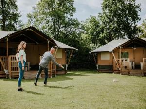 a man and a woman playing a game of frisbee in a yard at Luxury Family Tent with Play Area in Balkbrug +12 photos
