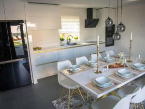 una cucina con tavolo, sedie bianche e lavandino di Magic Look with whirlpool and sauna a Donji Proložac