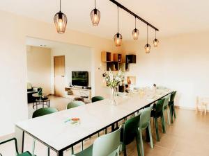 a large dining room with a long table and green chairs at Luxury holiday home in Zwevezele in Lichtervelde