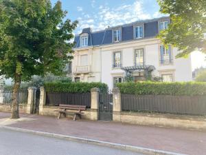 a white house with a bench in front of a fence at Amazing holiday home in the Heart of Vittel in Vittel