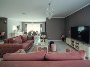 een woonkamer met roze banken en een flatscreen-tv bij Victoria with pool in Imotski in Ujevići