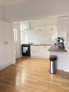 a kitchen with white cabinets and a wooden floor at Rose Cottage - Charming 2 Bedroom Home in Dunedin