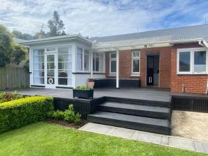 a home with a deck and a house at Rose Cottage - Charming 2 Bedroom Home in Dunedin