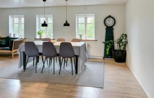 a dining room with a table and chairs and a clock at Amazing Home In Farsø With House A Panoramic View in Myrhøj